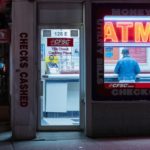 Neon sign in storefront advertising ATM inside and check cashing