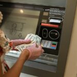 A woman receiving cash from an ATM.